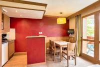eine Küche mit einer roten Wand sowie einem Tisch und Stühlen in der Unterkunft Quartier La Forêt - maeva Home - Appartement 2 pièces 5 personnes - Sélec 134 in Valmorel