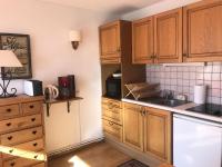 eine Küche mit Holzschränken und einer Arbeitsplatte in der Unterkunft Résidence Les Charmettes - Studio pour 2 Personnes 304 in Arc 1600