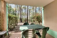 a table and chairs on a porch with a view of the woods at Résidence Lacanau Les Pins - maeva Home - Appartement 2 Pièces 5 Personnes 27 in Lacanau