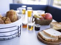 a table topped with baskets of bread and baskets of fruit at Tiercé Hotel in Cagnes-sur-Mer