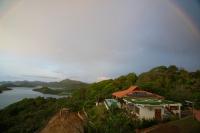 a rainbow over a house on a hill next to a river at Ciel y Miel in Colón