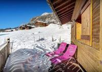 a pair of pink chairs in the snow next to a building at Chalet Sicoria - Les Congères in Le Grand-Bornand