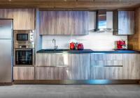 a kitchen with wooden cabinets and stainless steel appliances at Chalet Sicoria - Les Congères in Le Grand-Bornand