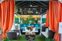 a patio with orange curtains and couches and a table at Hidden Gem Barbados in Christ Church