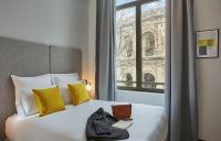 Habitación de hotel con cama con ordenador portátil y ventana en Appart&#39;hôtel Odalys City - Nîmes Arènes - Palais des Congrès, en Nimes