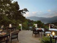 um deque com mesas e cadeiras e vista para as montanhas em Scenic, Munnar - IHCL SeleQtions em Munnar