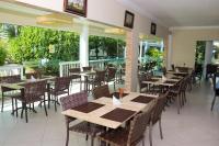 a restaurant with wooden tables and chairs and windows at Hotel Coral Beach in Tamandaré