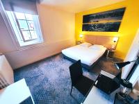 a hotel room with a bed and a desk with a laptop at Hôtel de la Gare - Restaurant Bistro Quai in La Roche-sur-Yon