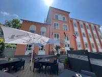 un restaurante con mesas y una sombrilla frente a un edificio en Hotel Am Mühlenteich, en Schwelm
