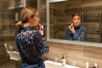 a woman standing in front of a mirror brushing her teeth at Domaine de la Forêt d&#39;Orient, Logis Hôtel, Restaurant, Spa et Golf in Rouilly-Sacey