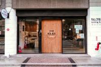 a store front with a wooden door on a street at Meeting Mates Hostel in Taipei