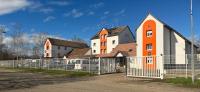an orange and white building with a fence at Hôtel NOROTEL in Brumath