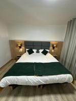 a bedroom with a large bed with green sheets and pillows at Hôtel NOROTEL in Brumath
