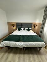 a bedroom with a large bed with a green blanket at Hôtel NOROTEL in Brumath
