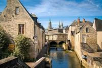 a river in a city with buildings and a bridge at Gite de la longue fosse in Mandeville-en-Bessin