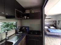 a kitchen with a sink and a bed in a trailer at Family&#39;s Camping Le Savoy in Challes-les-Eaux