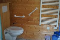 a bathroom with a toilet and a wooden wall at Family&#39;s Camping Le Savoy in Challes-les-Eaux