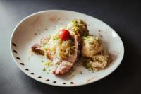 Un plato con un trozo de carne con una cereza encima. en Hotel Leonhard, en Nova Ponente