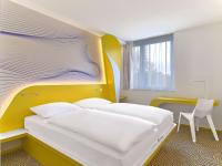 a bedroom with a white bed with a yellow headboard at prizeotel Hannover-City in Hannover
