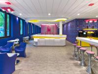 a restaurant with blue walls and pink and blue stools at prizeotel Hannover-City in Hannover