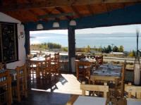 Un restaurante con mesas y sillas y un gran ventanal. en Solares Del Sur, en El Calafate