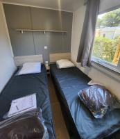 two beds in a small room with a window at Mobil-home (Clim, Tv)- Camping Narbonne-Plage 4* - 022 in Narbonne-Plage