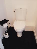 a white toilet in a bathroom with a black floor at Chambre privée Au pied des Vosges in Remiremont