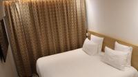 a bedroom with a bed with white sheets and pillows at Geographotel Paris-Roissy CDG Airport in Le Mesnil-Amelot
