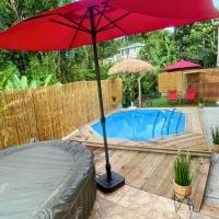 a red umbrella sitting next to a swimming pool at Villa Red Palmer -sauna jacuzzi in Gros-Morne