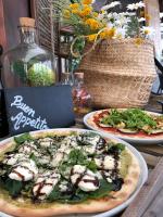 two pizzas on plates on a table with a pizza at Mareta Beach House - Boutique Residence in Sagres
