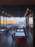 a row of tables and chairs in a restaurant with the ocean at Mareta Beach House - Boutique Residence in Sagres