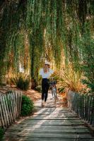 a woman walking a bike down a path under a tree at Le Phare in Les Portes