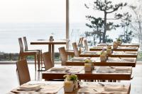 una fila de mesas y sillas de madera en un restaurante en SEAMARQ HOTEL, en Gangneung