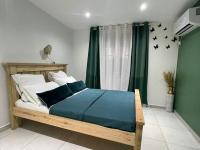 Schlafzimmer mit einem großen Holzbett mit blauer Bettwäsche in der Unterkunft Myosotis, charmant logement central avec piscine privée, wifi et parking gratuit in Petit-Bourg