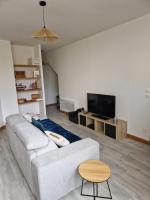 a living room with a white couch and a tv at Chez Aurélie et Bruno in Montceau-les-Mines