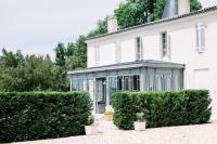 an exterior view of a white house with a conservatory at Gîte Château de Seguin in Lignan-de-Bordeaux