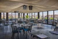 Un restaurante con mesas, sillas y ventanas. en Palace Catania | UNA Esperienze, en Catania