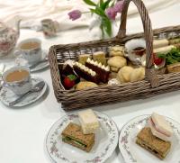 a table with plates of sandwiches and a basket of tea at Thatched Cottage Hotel in Brockenhurst