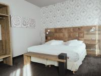 a bedroom with a large bed with a wooden headboard at Hôtel de Paris in Besançon