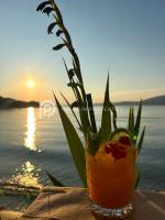 a drink sitting on a table with a sunset in the background at Villa Tranquility - Walk to the Beach with Infinity Pool in Porto Heli