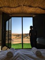 Una mujer parada frente a una ventana mirando el desierto. en Royal desert camp, en Al Raka