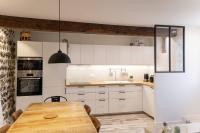 a kitchen with a wooden table and white cabinets at Maison et appartement attenant pour 10 personnes avec terrasse, cour et parking in Pau