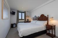 a bedroom with a large white bed and a table at Hotel Tugasa Arco de la Villa in Zahara de la Sierra