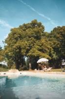 a swimming pool with an umbrella and chairs and a beach at Maison Lou Piade in Sarlat-la-Canéda