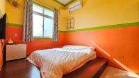 a bedroom with orange and green walls and a bed at Sea Front Homestay in Magong