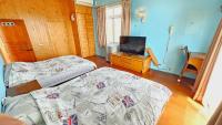 a bedroom with two beds and a television in it at Sea Front Homestay in Magong