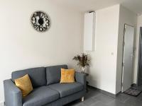 a living room with a couch and a clock on the wall at Chez NAYA- Proximité Paris- Métro 8 in Alfortville