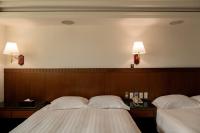 two beds in a hotel room with two lamps on the wall at Hub Hotel Kaohsiung Cisian Branch in Kaohsiung