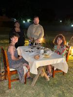 een groep mensen die 's nachts rond een tafel zitten bij Huaco Casa de Campo in Belén
