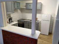 a kitchen with a brick counter and a white refrigerator at Confortable appart 5 mins centre de valenciennes in Anzin